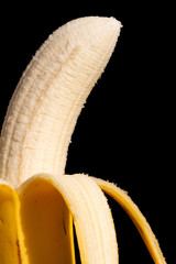 A half pealed banana close up with a black background