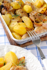 Baked potato with chicken legs in a foil tray