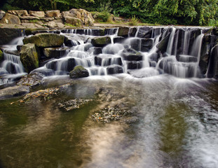 Fototapeta na wymiar Beautiful waterfall cascades over rocks in lush forest landscape