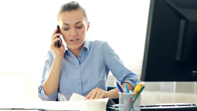 Angry businesswoman with documents screaming to cell phone