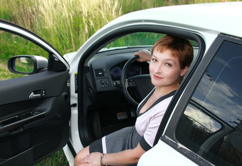 Beautiful smiling woman sitting behind the wheel of sport car wi