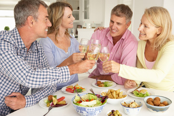 Obraz na płótnie Canvas Mid age couples enjoying meal at home