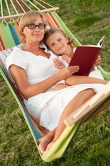 Mother with daughter reading a book in colorful hammock