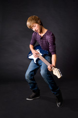 young man playing on guitar on dark background