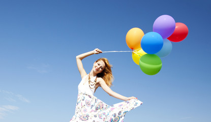 Obraz na płótnie Canvas Redhead girl with colour balloons at blue sky background.