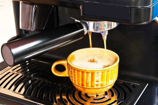 A ceramic cup of freshly brewed strong coffee pouring