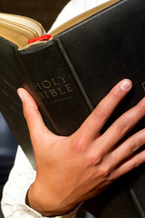 A close up of a man holding the holy bible