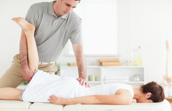 A chiropractor stretches a customer's leg