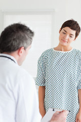 Woman in hospital gown talking to her doctor
