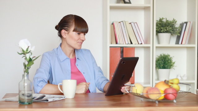 Young woman chatting on tablet computer in home