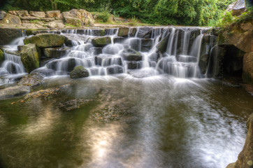 Fototapeta premium Beautiful waterfall cascades over rocks in lush forest landscape