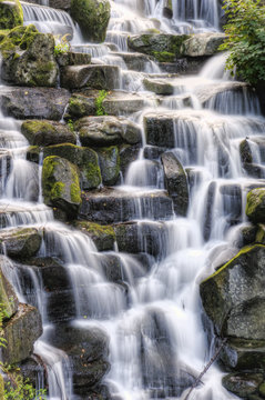 Fototapeta Beautiful waterfall cascades over rocks in lush forest landscape