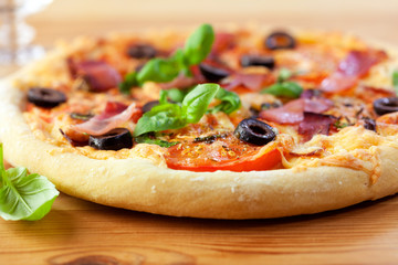 Pizza with tomatoes and ham on wooden background