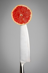 Red grape on the tip of a kitchen knife