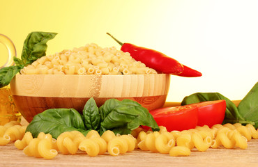 spaghetti with onion, spices  and basil on a yellow background