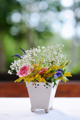 A vase full of assorted flowers outdoors