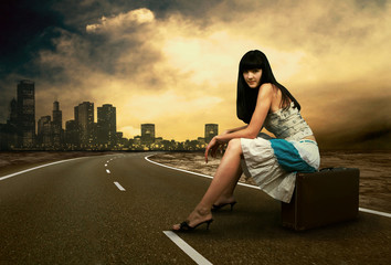 Fototapeta premium Young woman waiting on the road with her vintage baggage