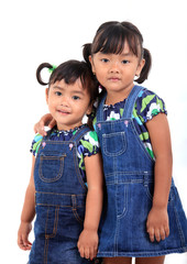 A cheerful studio portrait of two young Asian children laughing joyfully while posing for the camera. Both kids express pure happiness and fun, set against a clean white background. Perfect for themes