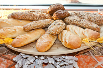 Loafs of fresh baked bread with wheat twig on plate