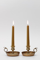 two burning candles in brass chambersticks