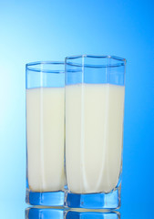 Tasty milk in glasses on blue background