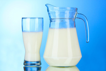 Tasty milk in jug and glass on blue background