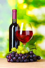 Obraz na płótnie Canvas Ripe grapes, bottle and glass of wine on green background
