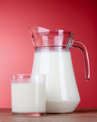 Pitcher and Glass with milk on red background