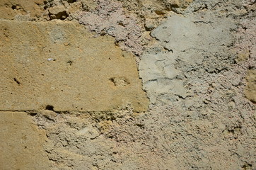 Wand eines alten Hauses mit Steinen und groben Putz