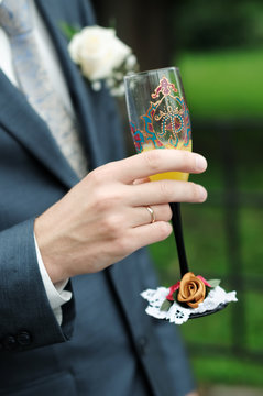 Groom is holding painting wedding champagne glasses