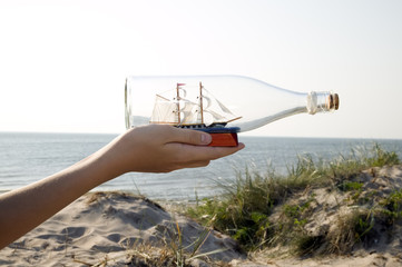 Man is holding miniature ship in bottle