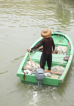 Man On Sampan Boat With Outboard Motor