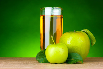 Glass of healthy fresh juice of apples on green background