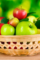 Fresh organic apples in basket on wooden table outside