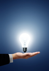 Light bulb in hand businessman on blue background