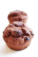 Two chocolate muffins on white background, shallow focus