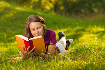 Naklejka na ściany i meble Beatiful woman with a book in the park