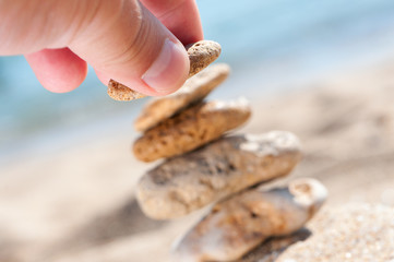 Stones on sand with hand.