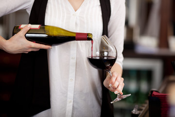 bedienung gießt rotwein in ein glas