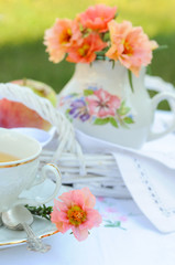 Still life with purslane flowers in a jug and a cup of tea.