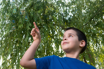 Kid playing with soap bubbles outdoor.