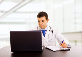 Fototapeta na wymiar A male doctor working at the desk in hospital office