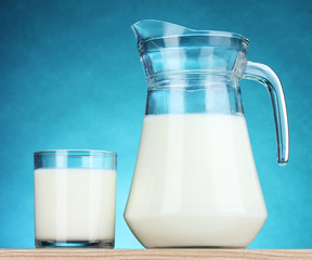 Tasty milk in jug and glass on blue background
