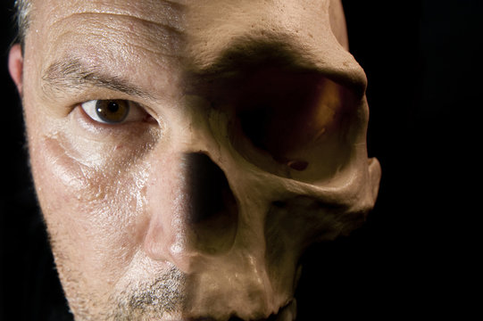 Scary Haalloween concept of half face half skull visible on dark
