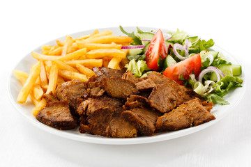 Grilled meat with French fries and vegetables