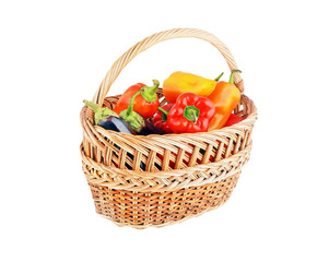 Fresh sweet red pepper and eggplant in a wattled basket on white