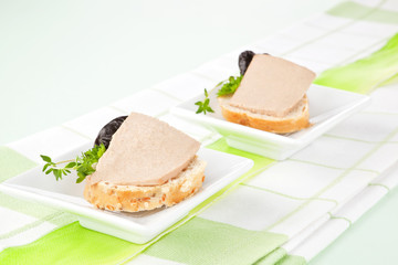 White bread pieces with pate and fresh herbs.