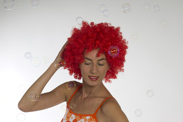 Beautiful woman in an orange wig with soap bubbles