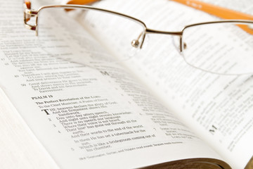 Holy Bible opened with glasses on it