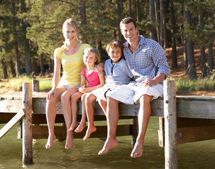 Fototapeta na wymiar Młoda rodzina siedzi przy jeziorze